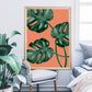 Monstera Orange Botanical Illustration Print sitting on a chair in a bedroom